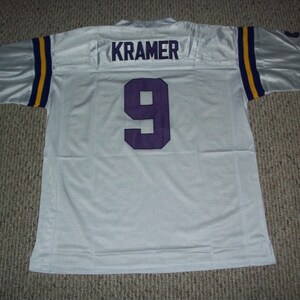 May include: White football jersey with purple and gold trim. The number 9 and the name "KRAMER" are printed on the back in purple.