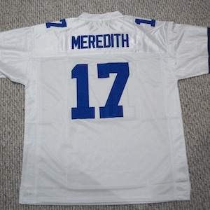 May include: White football jersey with blue lettering. The jersey has the number "17" and the name "MEREDITH" on the back.