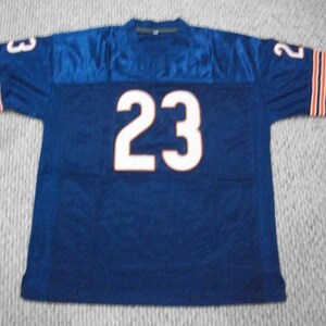 May include: A navy blue football jersey with white number 23 on the back. The jersey has orange and white stripes on the sleeves.