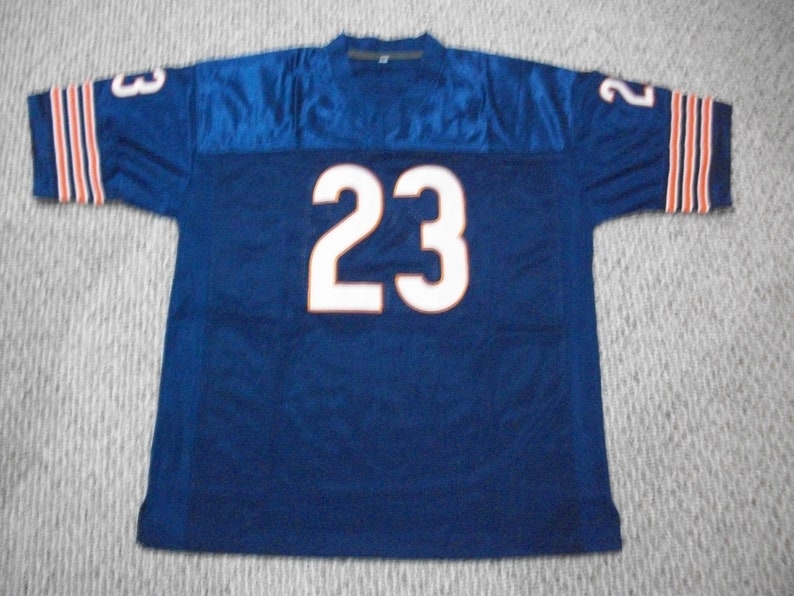 May include: A navy blue football jersey with white number 23 on the back. The jersey has orange and white stripes on the sleeves.