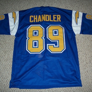 May include: Blue mesh jersey with the name "CHANDLER" and the number "89" in gold with white trim. The sleeves have a white stripe with a yellow lightning bolt. The number "8" is on each sleeve.
