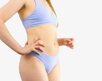 Könnte beinhalten: Hellblaues Dessous-Set, bestehend aus einem Bralette mit dünnen Trägern und passendem hoch geschnittenem Slip. Das Set ist aus einem weichen, einfarbigen Stoff gefertigt. Der Hintergrund ist weiß.