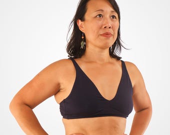Op de afbeelding: Een vrouw draagt ​​een donkerblauwe, draadloze bh met een V-hals. De bh heeft een glad, naadloos ontwerp.