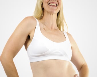 Può includere: Reggiseno sportivo bianco con scollatura rotonda e design a incrocio sul davanti. Il reggiseno è realizzato in un tessuto liscio. L'immagine è ambientata su uno sfondo bianco.
