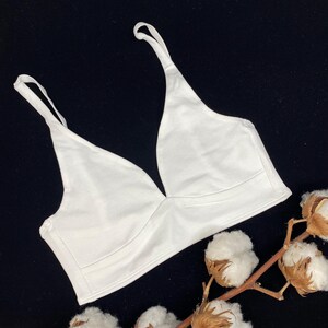 Op de afbeelding: Witte katoenen bralette met verstelbare bandjes en een diepe V-hals.