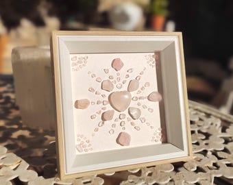 May include: A framed pink crystal art piece with a heart-shaped crystal in the center. The crystal is surrounded by smaller pink crystals arranged in a radiating pattern.