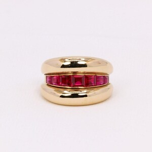 Peut inclure: Une bague en or avec une bande de rubis rouges sertie dans un design lisse et arrondi.