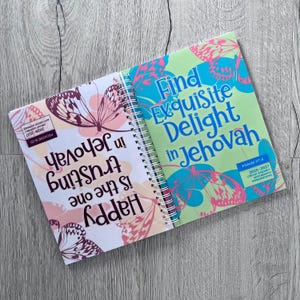 Peut inclure: Un carnet à spirales illustré de papillons et de texte. La page de gauche indique Happy is the one trusting in Jehovah, et la page de droite indique Find Exquisite Delight in Jehovah. Les deux pages comportent de petites étiquettes rectangulaires.