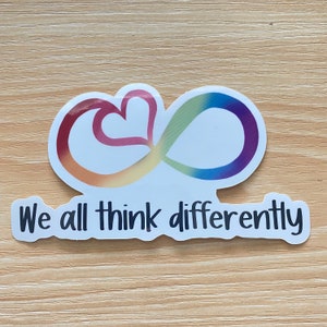 May include: A white sticker with a rainbow infinity symbol and a heart inside. The text "We all think differently" is below the symbol.