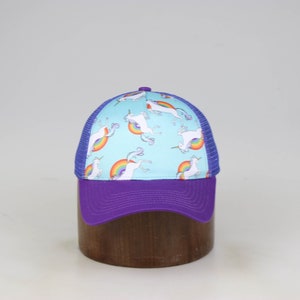 May include: A blue and purple trucker hat with a white unicorn and rainbow pattern.