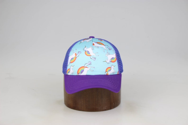 May include: A blue and purple trucker hat with a white unicorn and rainbow pattern.