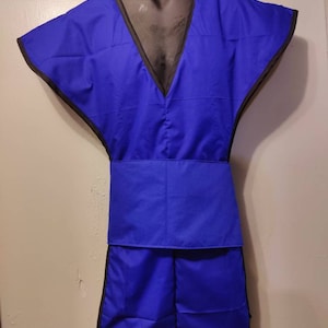 Puede incluir: Prenda de protección contra radiación médica azul, exhibida en un maniquí. La prenda tiene cuello en V, mangas cortas y cinturón. Los bordes están ribeteados con tela negra.