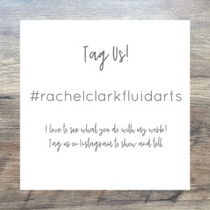 Pode incluir: Texto branco em fundo cinza com as palavras "Tag Us!" e "#rachelclarkfluidarts". O texto abaixo diz "Adoro ver o que voc&ecirc; faz com meu trabalho! Marque-nos no Instagram para mostrar e contar."