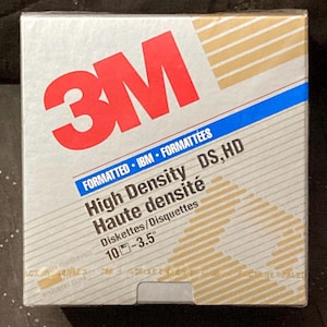 May include: A box of 10 3.5 inch high density floppy disks, formatted for IBM computers. The box is silver with a red 3M logo and the text "FORMATTED IBM FORMATTÉES High Density DS, HD Haute densité Diskettes/Disquettes 10-3.5" printed on it.