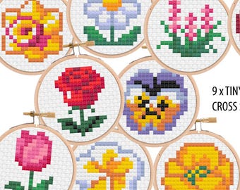 以下が含まれることがあります： 木製のフープに入った小さな花のクロスステッチパターン9つ。花には、赤いポピー、ピンクのチューリップ、黄色のバラ、白いデイジーが含まれます。テキストは「9 x TINY FLOWERS CROSS STITCH PATTERNS」と書かれています。