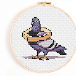 May include: A cross-stitch pattern of a gray and purple pigeon wearing a yellow bagel around its neck.