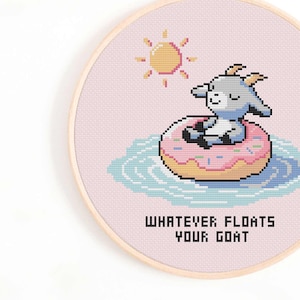 Könnte beinhalten: Ein Kreuzstichmuster mit einer Cartoon-Ziege, die einen rosafarbenen Donut als Schwimmreifen in einem blauen Pool trägt. Die Sonne scheint über der Ziege. Der Text "Whatever floats your goat" befindet sich unter der Ziege.