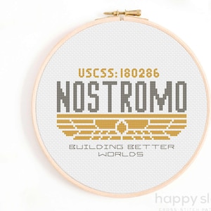 以下が含まれることがあります： 映画「エイリアン」の宇宙船ノストロモのクロスステッチパターン。パターンには、船の名前、登録番号、そして「Building Better Worlds」の文字が描かれています。