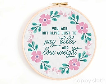 Puede incluir: Un aro de bordado blanco con un diseño de corona floral y el texto "You are not alive just to pay bills and lose weight".