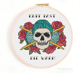 May include: A cross-stitch pattern featuring a skull wearing a blue knit hat, surrounded by red roses and yarn balls. The text "Knit Fast Die Warm" is above and below the skull.