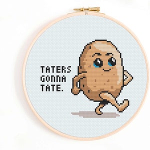 May include: Cross-stitch embroidery in a wooden hoop features a cartoon potato with arms and legs, walking with a smile. The text "TATERS GONNA TATE" is stitched in black above the potato. The background is light blue.