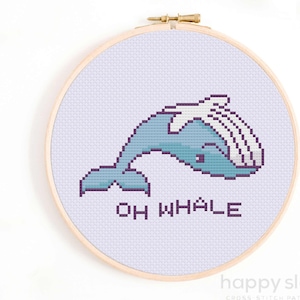 May include: Cross stitch pattern featuring a cartoon whale with the text "Oh Whale" in purple lettering. The whale is blue and white and is stitched on a light purple background.