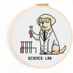 May include: Cross-stitch embroidery in a wooden hoop. The design features a pixelated yellow Labrador wearing glasses and a lab coat, holding a test tube. The text "SCIENCE LAB" is below the dog. The test tubes contain red and yellow liquid.