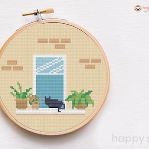 May include: Cross-stitch pattern of a black cat sitting on a windowsill with potted plants. The window is blue and has a white grid pattern. The background is a beige brick wall.