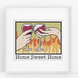 Puede incluir: Patrón de punto de cruz con dos copas de vino tinto, brindando, con llamas detrás. El texto "Home Sweet Home" está debajo de las copas.