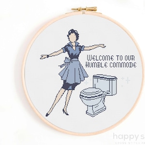May include: Cross stitch pattern featuring a retro-style woman in a blue dress standing next to a toilet. The text reads "Welcome to our humble commode".