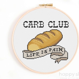 Op de afbeelding: Borduurpatroon met een brood en de tekst "Carb Club Life is Pain" op een banner.