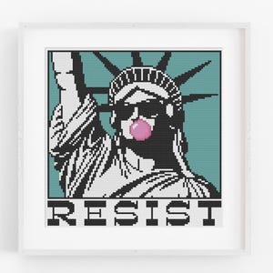 Peut inclure: Impression d'art encadrée représentant la Statue de la Liberté pixelisée, portant des lunettes de soleil et soufflant une bulle de chewing-gum rose. Le mot "RESIST" est imprimé en bas. Fond turquoise.