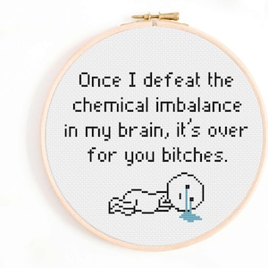 Puede incluir: Aro de punto de cruz con el texto "Once I defeat the chemical imbalance in my brain, it's over for you bitches." Una pequeña figura llorando en la parte inferior. El aro es de madera.