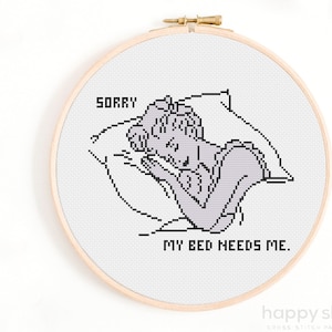 May include: A black and white cross stitch pattern of a person sleeping in bed with the text "Sorry, my bed needs me."