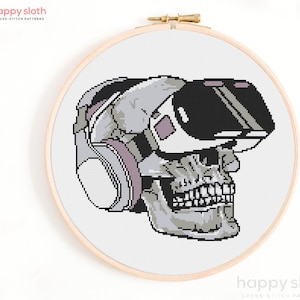 Puede incluir: Un patrón de punto de cruz de una calavera con un casco de realidad virtual. La calavera es gris y blanca, y el casco es negro y blanco. El patrón está sobre un fondo blanco.