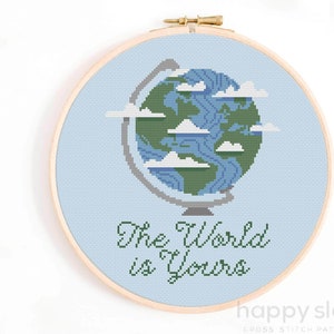 Op de afbeelding: Een blauw en groen kruissteekpatroon van een wereldbol met wolken en de tekst "The World is Yours".