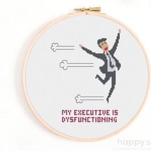 Può includere: Schema di punto croce con un uomo dei cartoni animati in abito che salta con le braccia alzate. Il testo "My executive is dysfunctioning" è sotto l'immagine.