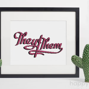 May include: A framed cross-stitch pattern with the words "They/Them" in pink cursive lettering on a white background.
