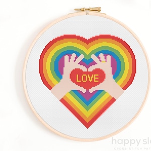 a cross stitch picture of two hands holding a heart