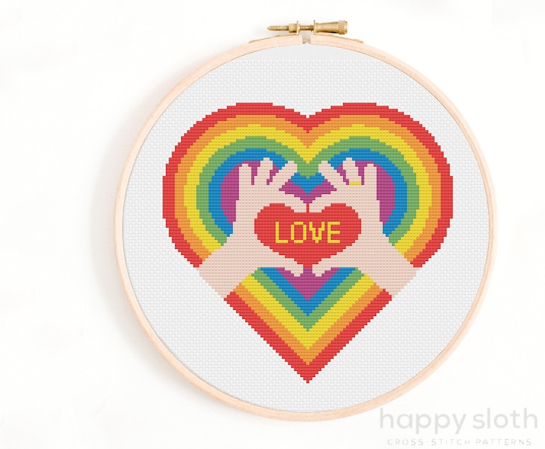 a cross stitch picture of two hands holding a heart