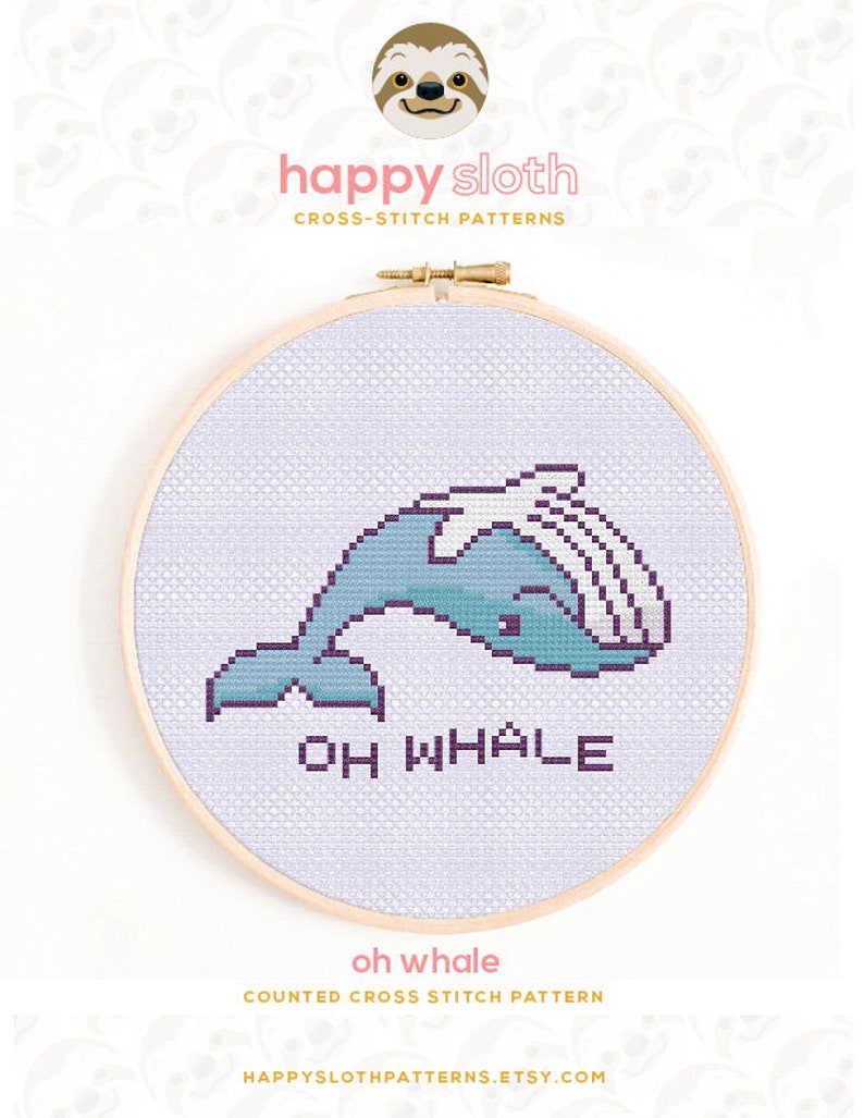 May include: Counted cross stitch pattern of a blue whale with the text "Oh Whale" in purple. The pattern is displayed in a wooden embroidery hoop.