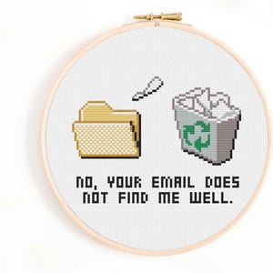 Op de afbeelding: Kruissteekkunst in een hoepel met gepixelde afbeeldingen van een map, een prullenbak met een recyclingsymbool en een papieren vliegtuig. De tekst luidt: "NO, YOUR EMAIL DOES NOT FIND ME WELL."