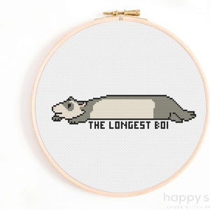 May include: Cross stitch pattern featuring a cartoon ferret lying down with the text "THE LONGEST BOI".