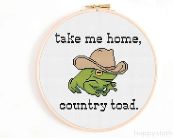 Könnte beinhalten: Kreuzstichmuster mit einem grünen Frosch, der einen braunen Cowboyhut trägt. Der Text "take me home, country toad." befindet sich unter dem Frosch.