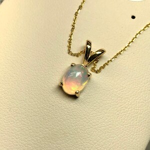 May include: A gold chain necklace with a pendant featuring a white opal gemstone.