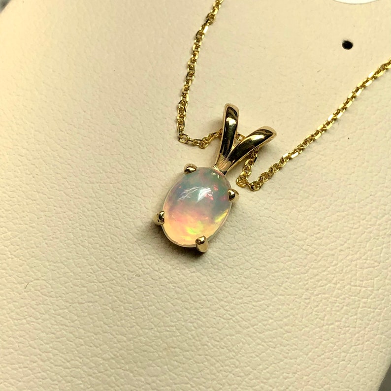 May include: A gold chain necklace with a pendant featuring a white opal gemstone.
