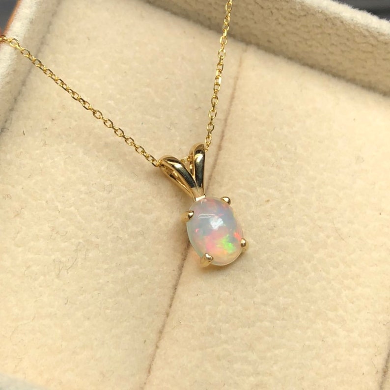 May include: A gold chain necklace with a small oval opal pendant.