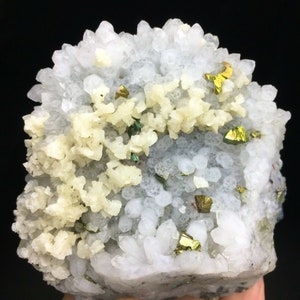 Könnte beinhalten: Ein Cluster aus weißen Quarzkristallen mit einer Schicht kleinerer, cremefarbener Kristalle. Der Cluster ist mit mehreren schillernden, goldfarbenen Pyritkristallen verziert.