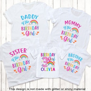 May include: Set of five white t-shirts with rainbow and unicorn designs. The shirts say "Daddy of the Birthday Girl", "Mommy of the Birthday Girl", "Sister of the Birthday Girl", "Birthday Girl" with the number 3 and the name Olivia, and "Brother of the Birthday Girl".