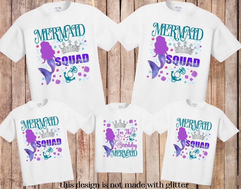 K&ouml;nnte beinhalten: Wei&szlig;e T-Shirts mit einem Meerjungfrauen-Design. Die Shirts zeigen die Worte "MERMAID SQUAD" in T&uuml;rkis und Lila, eine Meerjungfrauen-Illustration, eine Krone und einen Anker. Ein Shirt tr&auml;gt die Aufschrift "I'm the Birthday Mermaid". Der Text "this design is not made with glitter" steht unten.